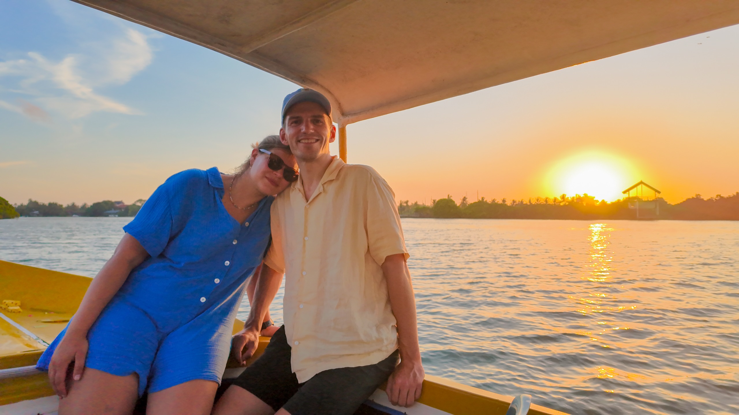Sunset over Negombo Lagoon during an evening boat tour — golden light reflecting on the water with palm trees on the horizon, Sri Lanka